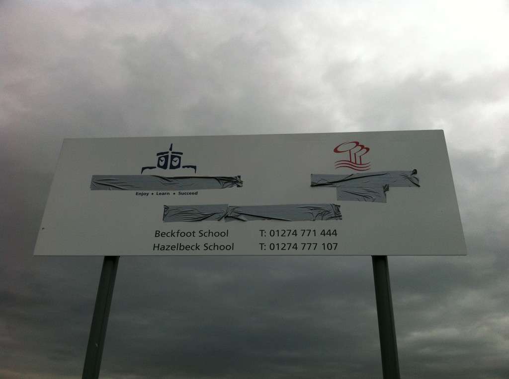 An image of a school sign with parts obscured by gaffer tape